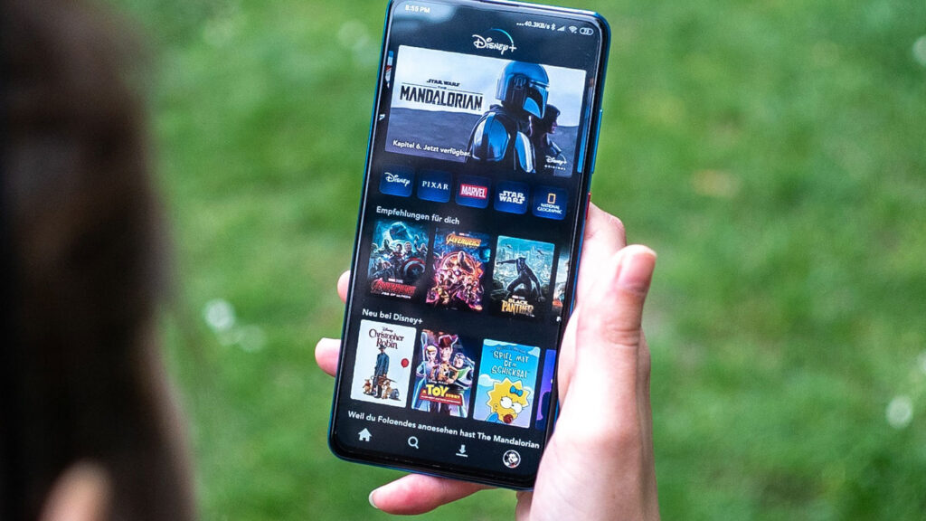 Photograph of woman holding phone streaming the Mandalorian on Disney+