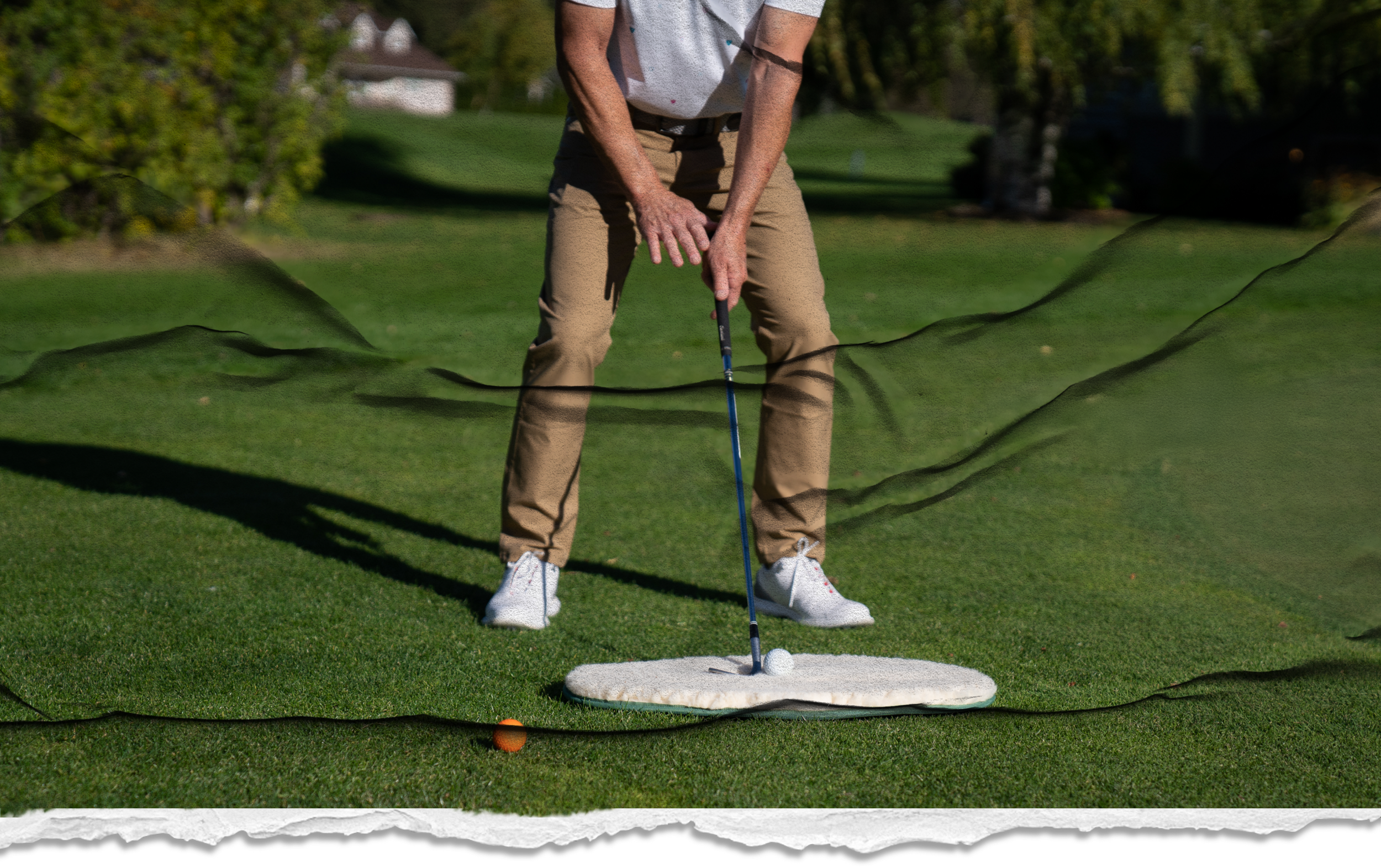 Man in khanki pants lining up a practice golf shot